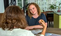 Une femme aux cheveux bouclés penche la tête sur le côté