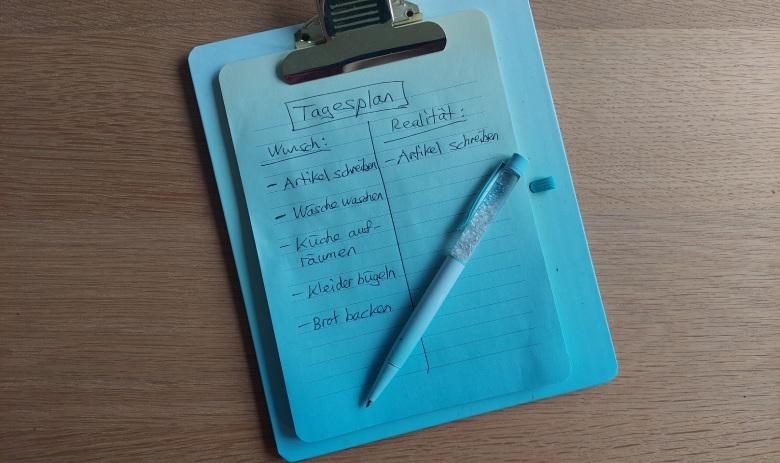 Kleines Clipboard mit einer Notiz. Als Titel steht "Tagesplan", Wunsch und Realität sind einander gegenübergestellt. Die Wunschliste enthält fünf Aufgaben, auf der Seite "Realität" ist allein der erste Punkt aus den Wünschen übertragen.